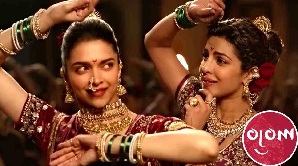Deux danseuses en saris bordeaux, mains levées et regard face caméra