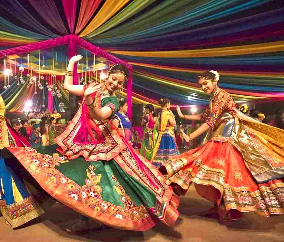 Danseuses de garba en jupes brodées sous un chapiteau aux tissus colorés