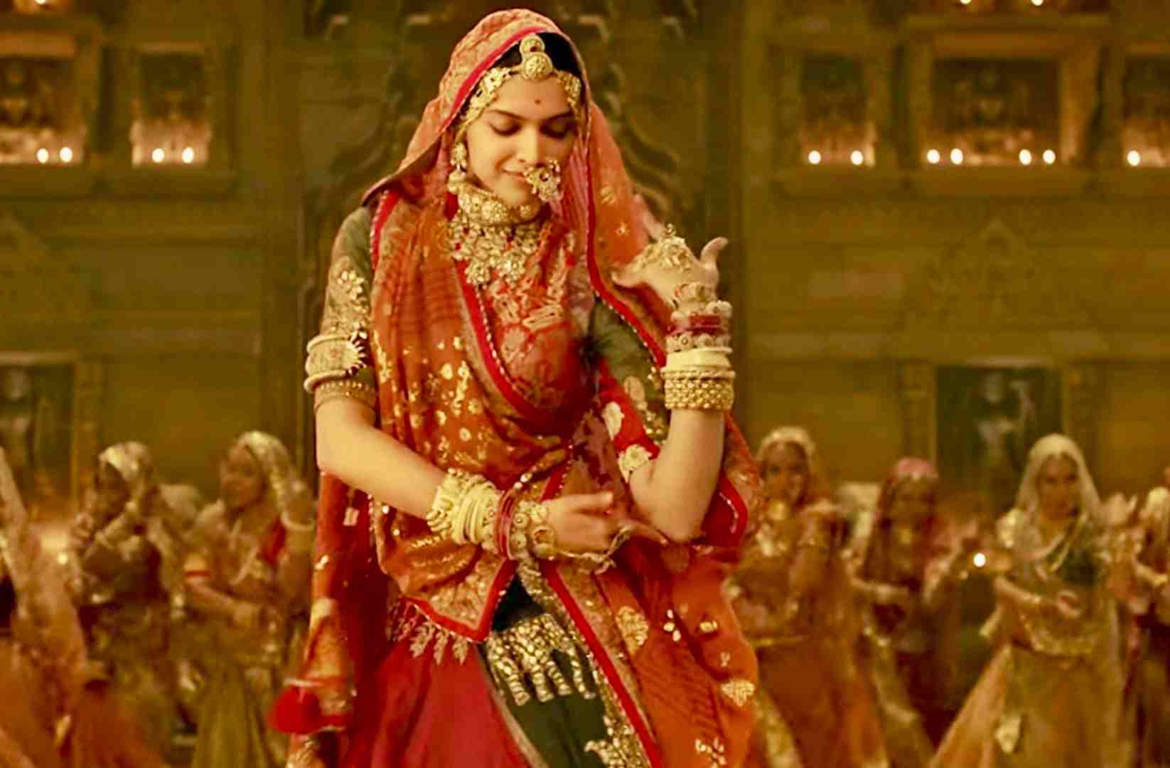Danseuse de ghoomar en jupe rouge et or, dans une cour de palais
