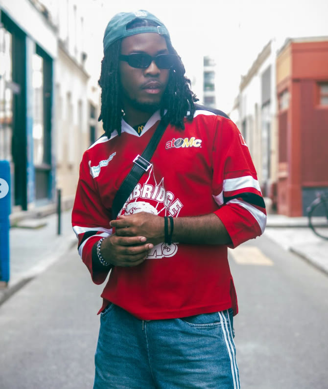 Guillaume en casquette et maillot de sport rouge, dans une rue