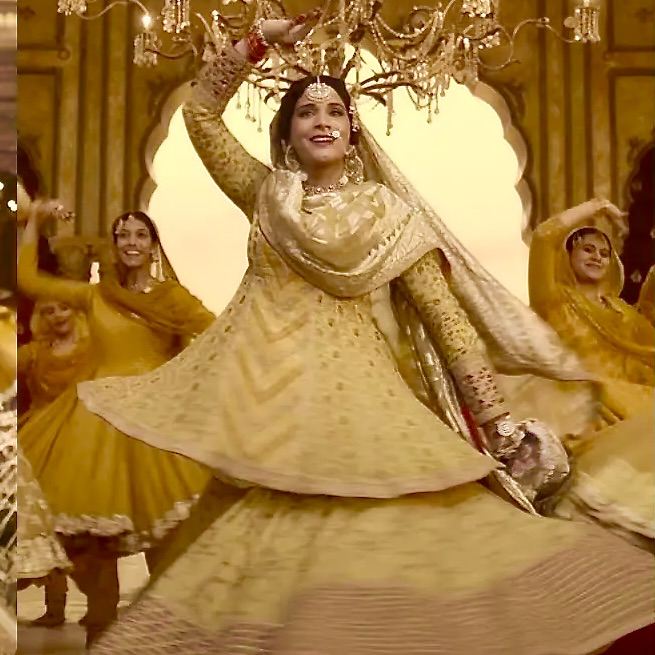 Une danseuse bras levés au-dessus de la tête, entourée de danseuses en jaune