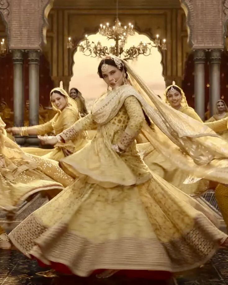 Une danseuse en lehenga jaune pâle en pleine rotation, la jupe déployée en cercle
